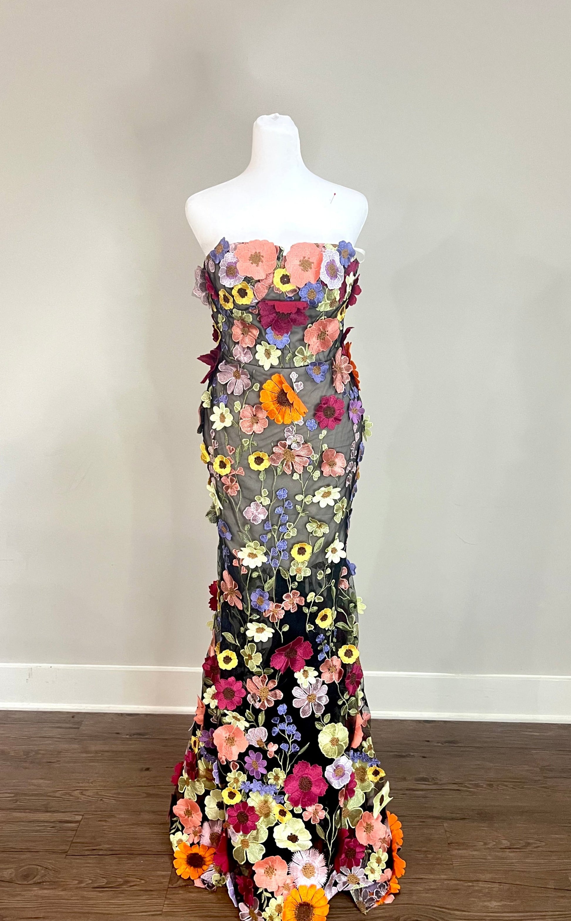 A stunning back view of a wedding guest dress featuring intricate floral embroidery in vibrant colors. The dress showcases a lace-up detail, adding a touch of elegance and customization to the fit. Black tie gown, evening gown, mermaid black tie dress, formal gown mermaid