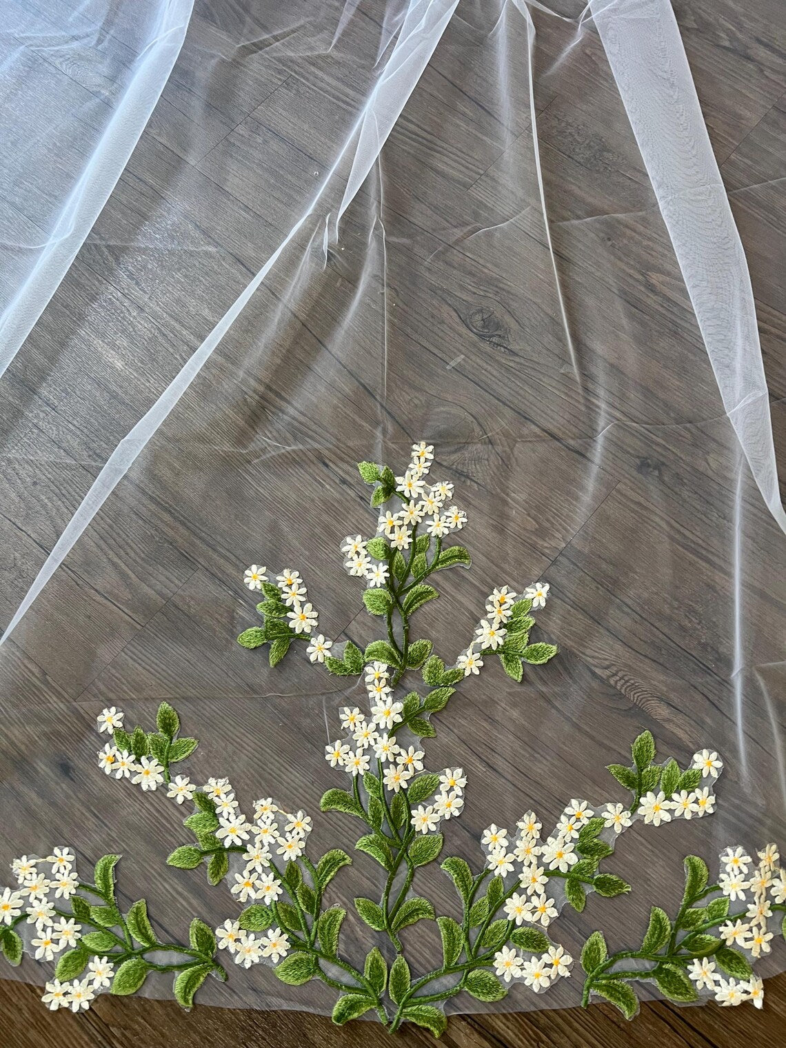 Close up of the veil and its tulle detailed in green and white flowers