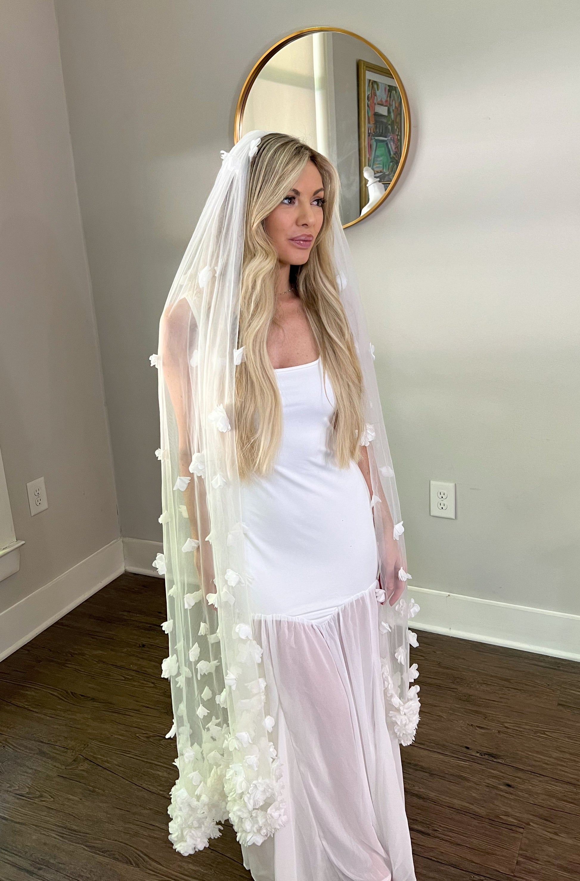 Knee Length Wedding Veil with White Flowers on blonde in bridal showroom.