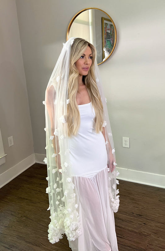 Knee Length Wedding Veil with White Flowers on blonde in bridal showroom.
