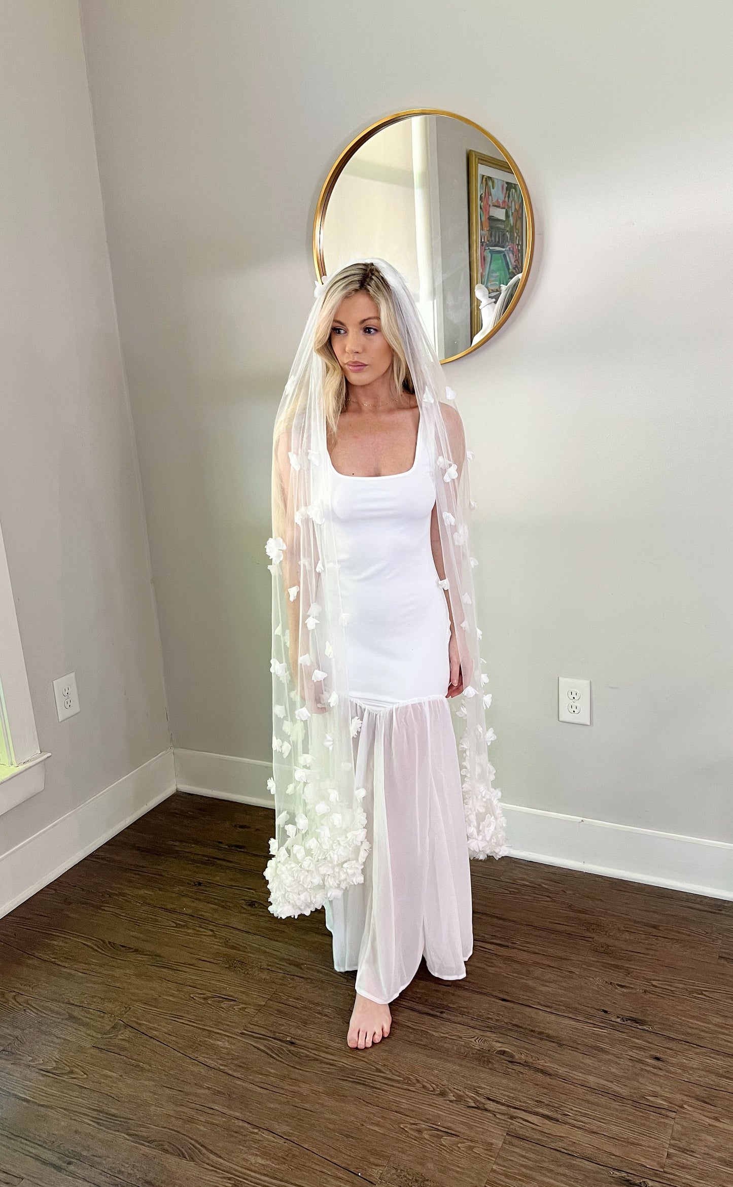 Knee Length Wedding Veil with White Flowers flowing across blonde woman's shoulders in bridal showroom.