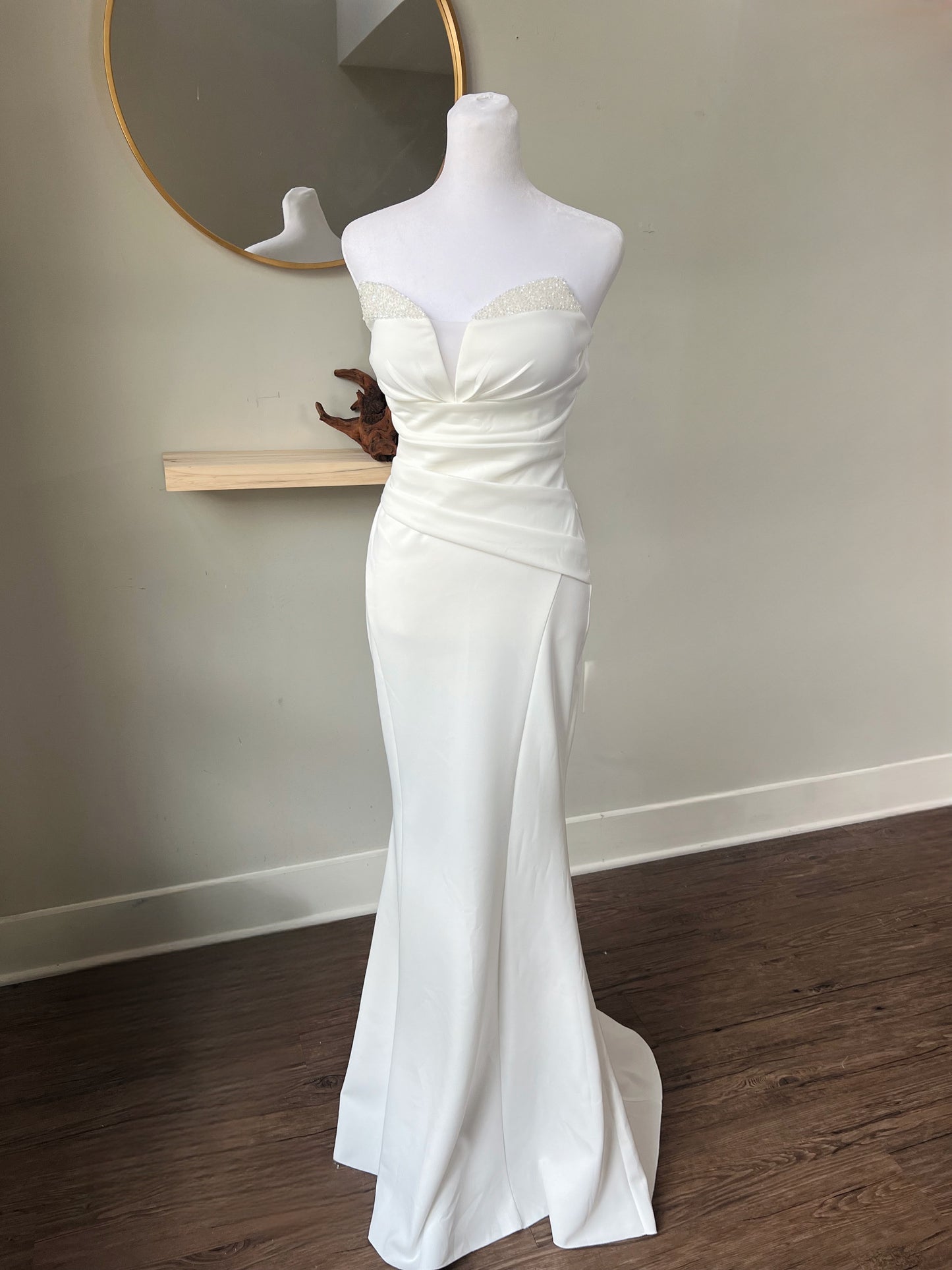 Three-quarter front view of a strapless ruched mermaid wedding dress with a sweetheart neckline and elegant fitted design on a mannequin.