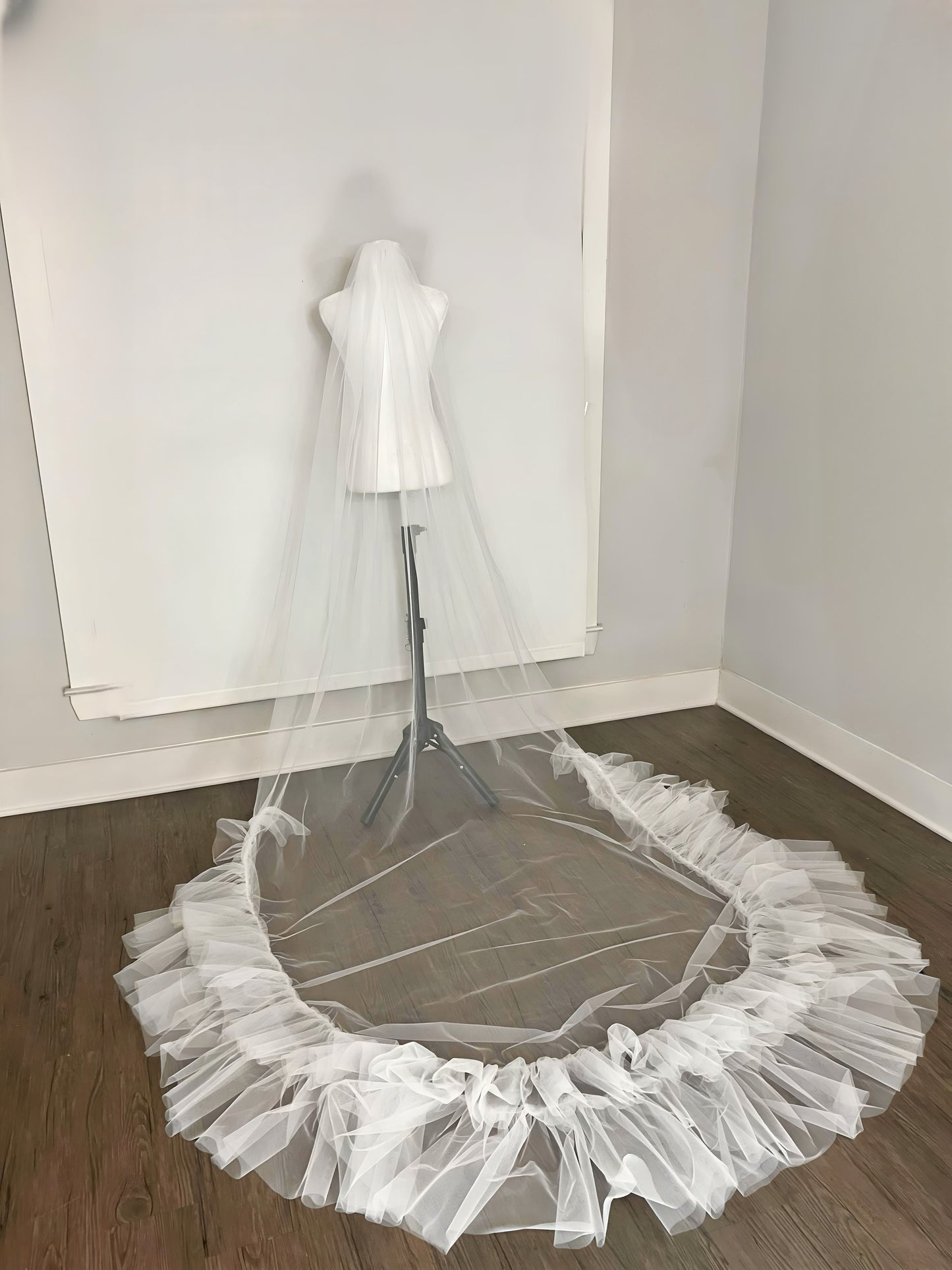 Wedding Veil half ruffles on hardwood floor in showroom. Cathedral length veil
