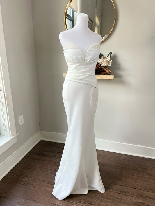 Strapless ruched mermaid wedding dress displayed on a white mannequin, featuring a sweetheart neckline and fitted silhouette.