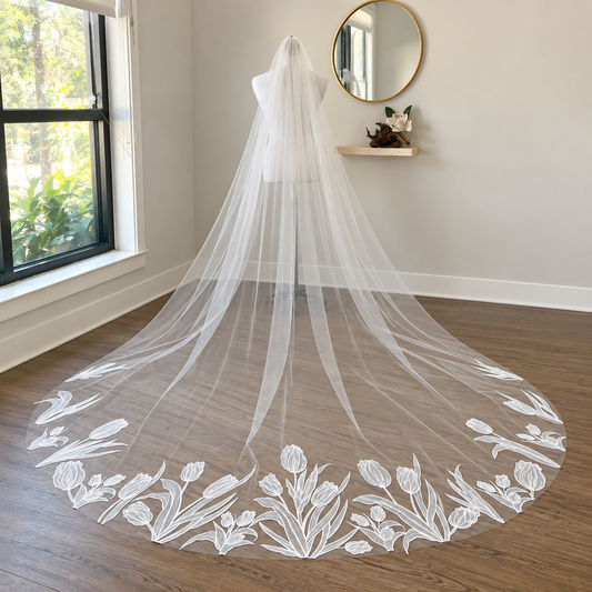 Sheer cathedral veil with white tulip embroidery along the hem, back view in Haus of Lace studio setting